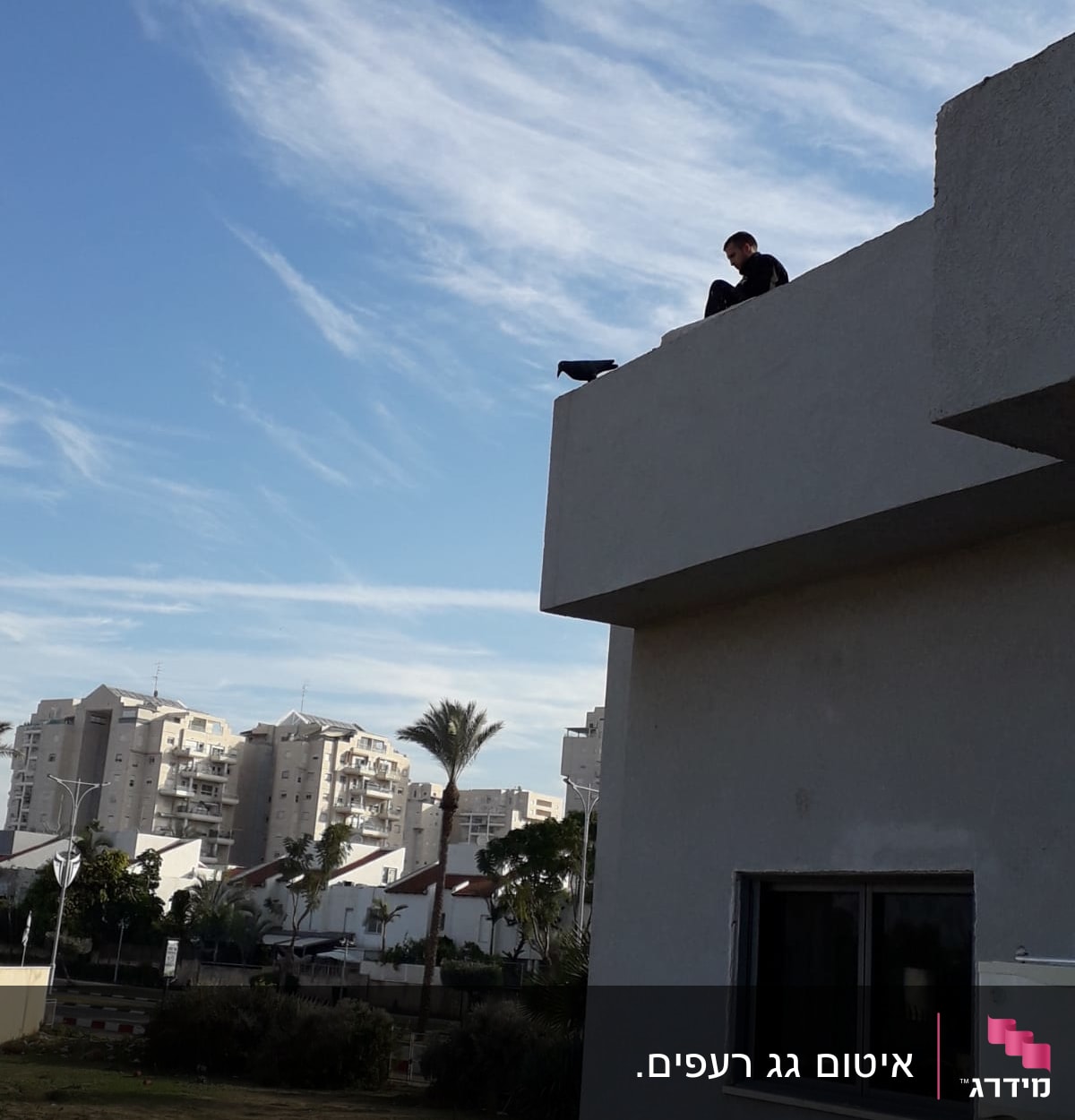 אדם יושב על גג מבנה עם שמיים בהירים